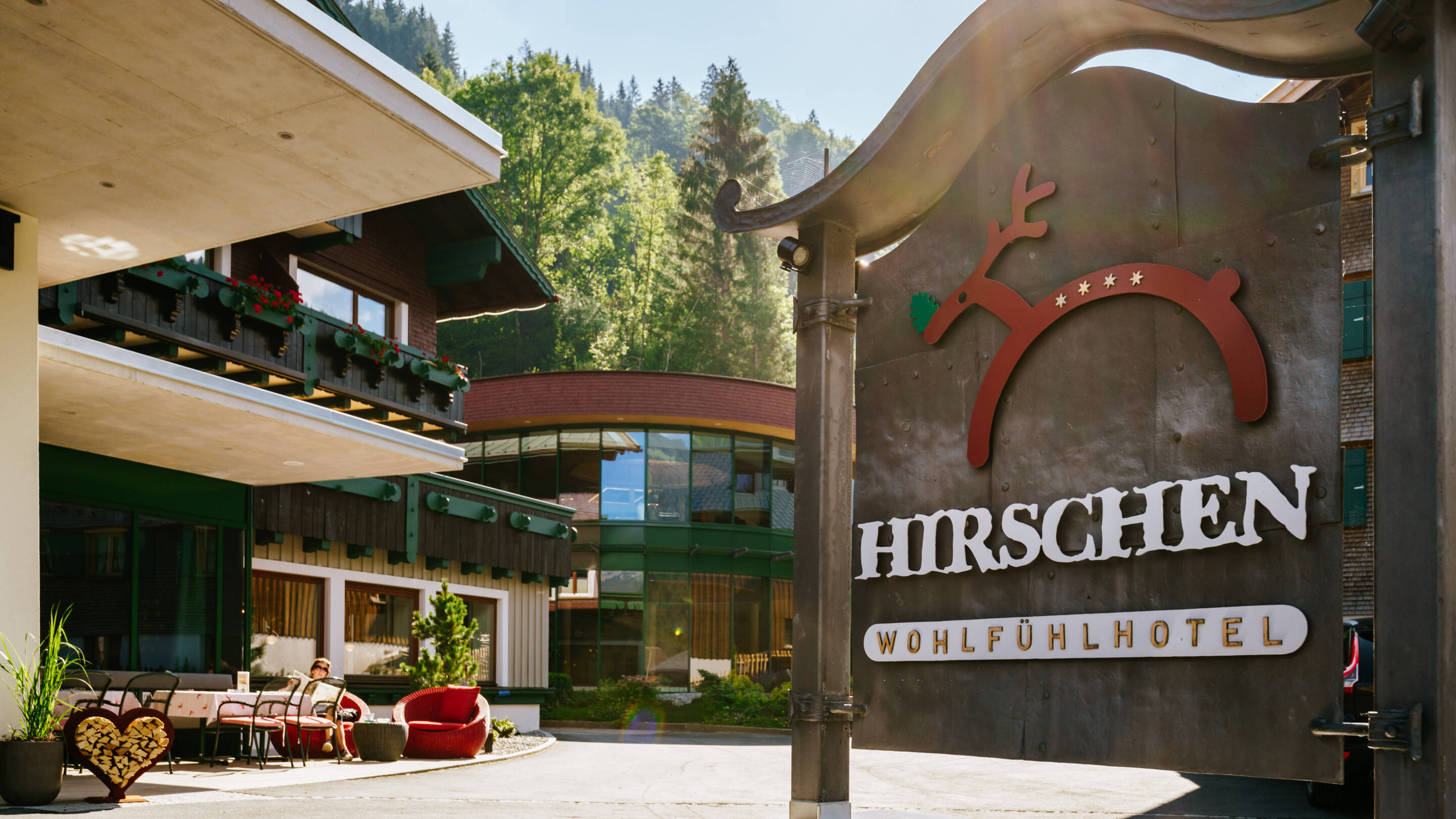 Eingang zum Hirschen Wohlfühlhotel Haupteingang des Hirschen Wohlfühlhotels umgeben von grüner Vegetation und einem einladenden Schild